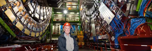 彼得·希格斯站在欧洲核子彩票购买中心的大型强子对撞机前，他提出的希格斯玻色子就是在这里被发现的.
