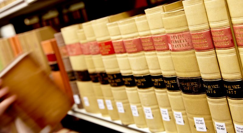 Close-up of hand pulling law book off shelf