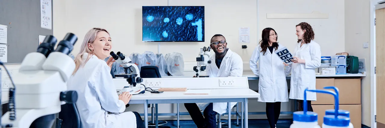 4 students in lab coats in a laboratory