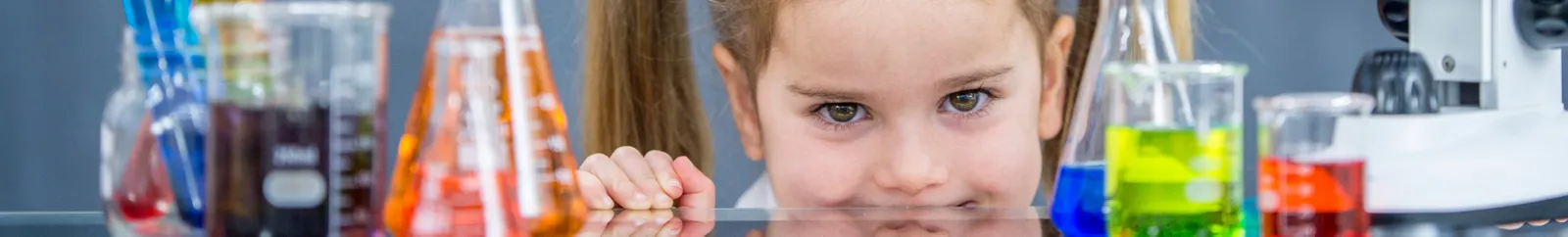 Child smiling surrounded by test tubes and other science equipment