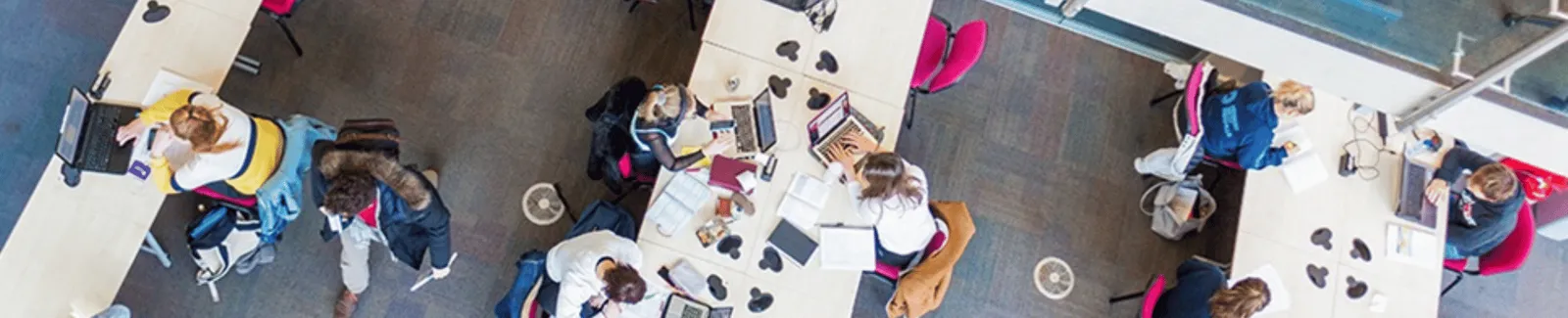 A group of students at tables with laptops seen from above.