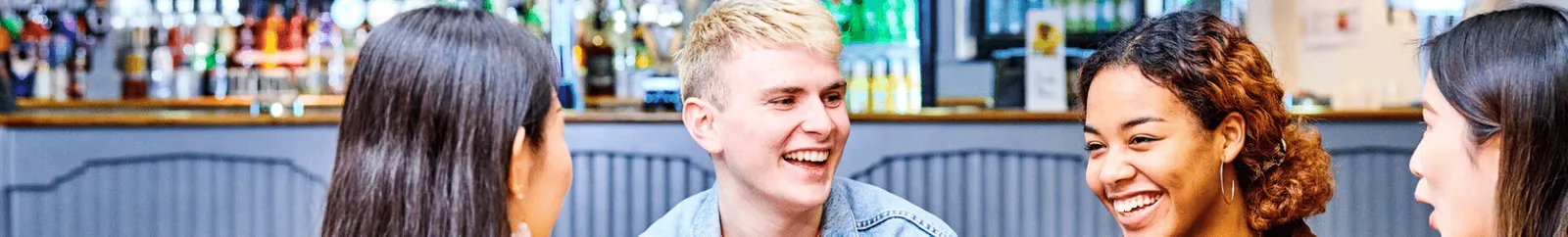 Four students laughing in a college bar