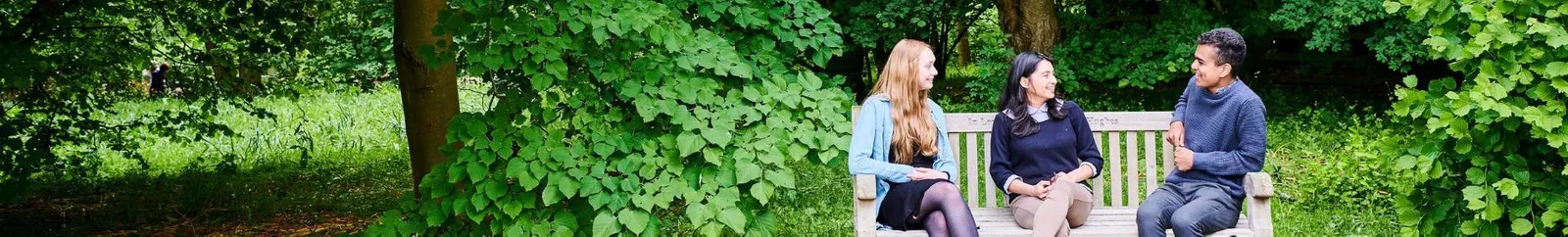 Students sitting on an outdoor bench in the gardens
