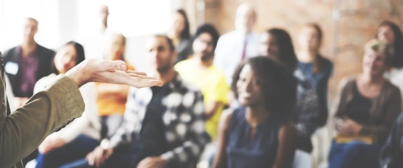 Blurry image of classroom with students with focus on a hand