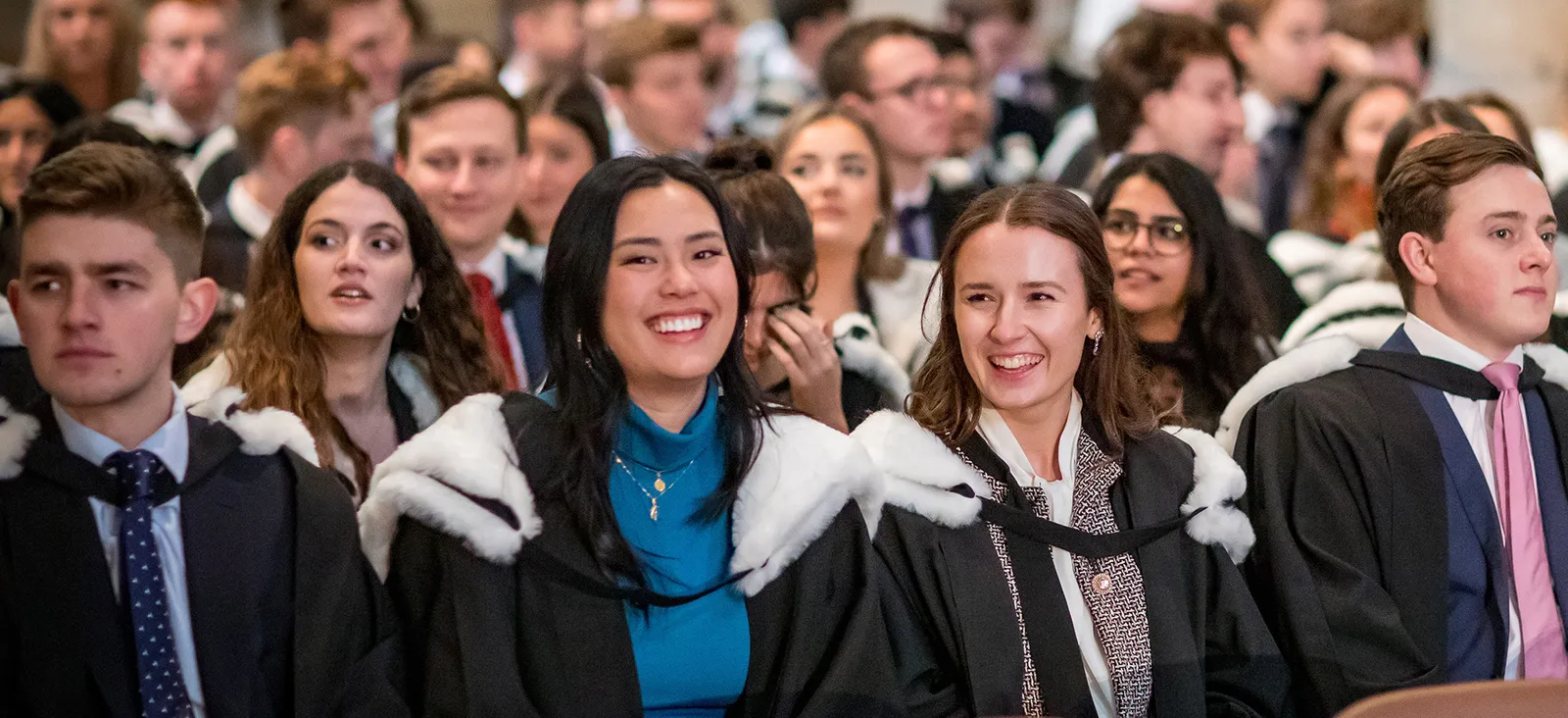 Graduates smiling while sat in the Cathedral during Congregation
