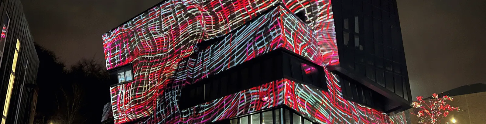 The Ogden Centre at night illuminated by red and pink art