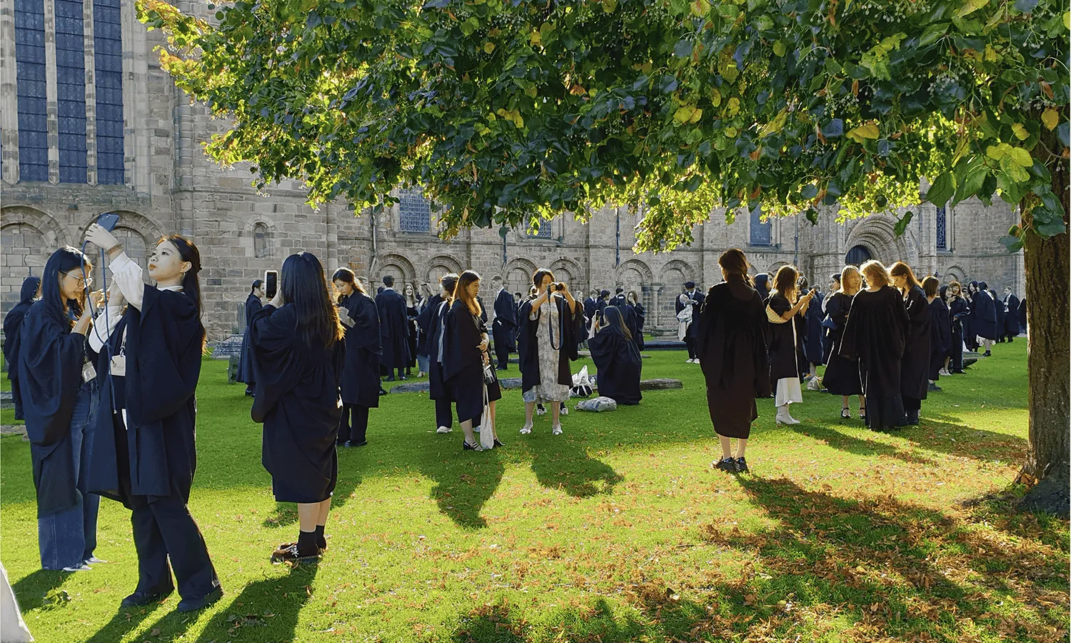 Students in robes on the grass outside Durham Cathedral