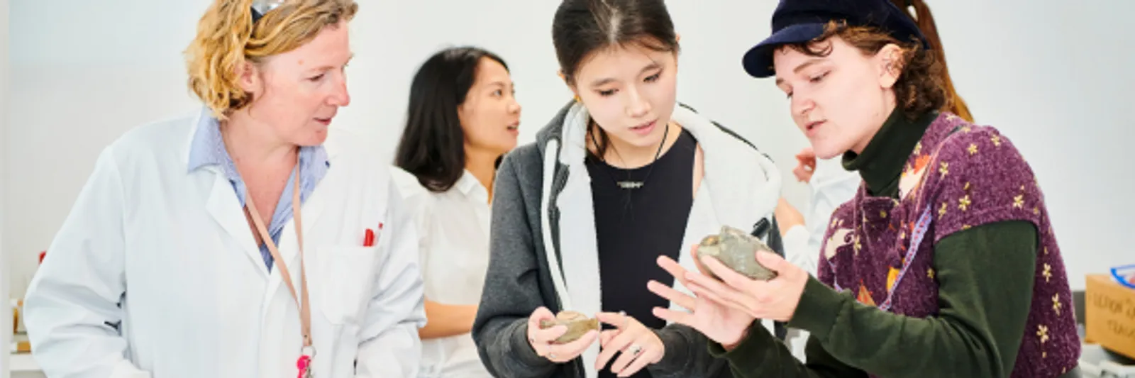 Three Students and Science Professor inspecting a rock