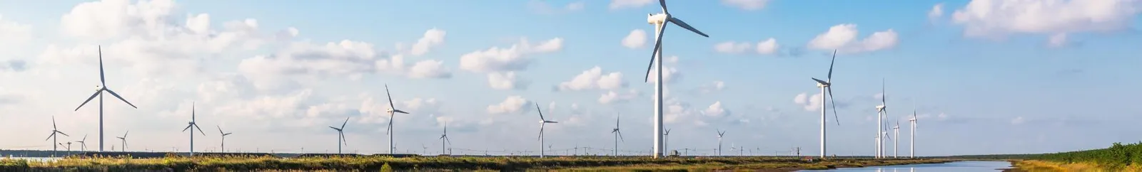 Wind turbines against a blue sky reflected in ground water