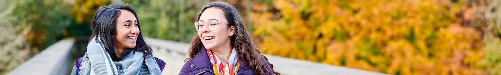 Two students laugh and chat as they cross Kingsgate Footbridge