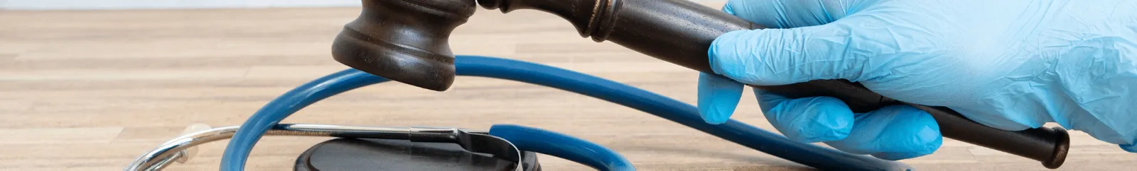 A stethoscope and gavel held by a gloved hand