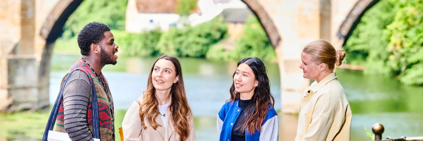 Four students chatting by the Durham riverside