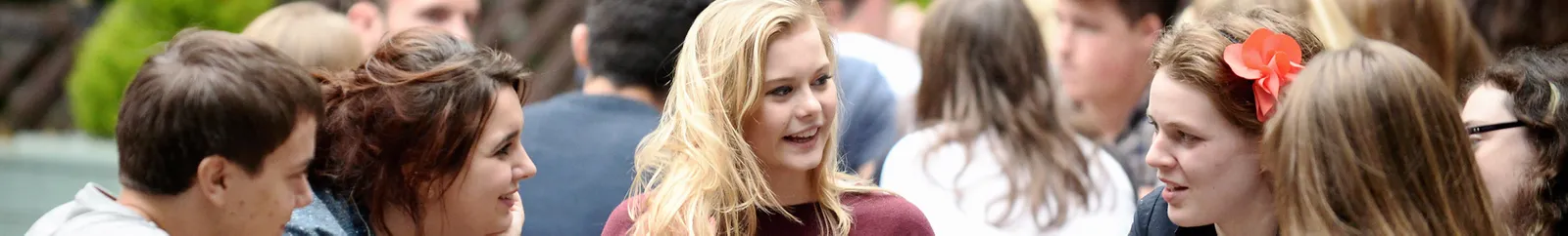 A group of students around a table chat enthusiastically about what they have been up to