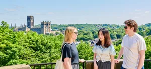 Three students chatting with Durham Cathedral in the background