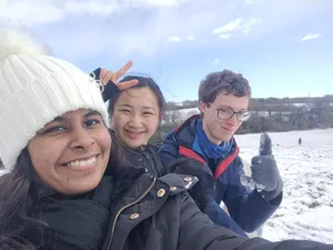Three students in snow smiling at camera
