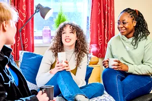 Three students sat chatting and laughing in their accommodation