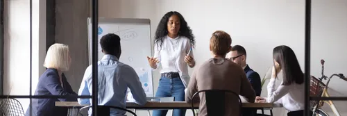 Black woman giving corporate presentation in front of a multiracial team