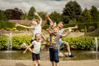Four children jumping into the air and smiling, while at the Botanic Garden.