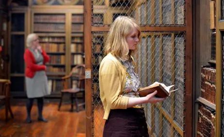 A person exploring the books at a bookcase in Cosin's Library.