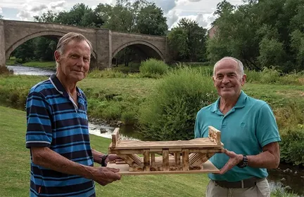Picture of the two Piercebridge Divers holding a model of a bridge.
