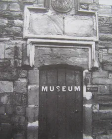 A black and white photograph of a door at the Almshouse on Palace Green with the word Museum on the door.