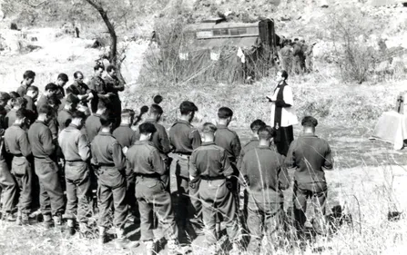 black and white photograph of a group of soldiers gathered around an army chaplain