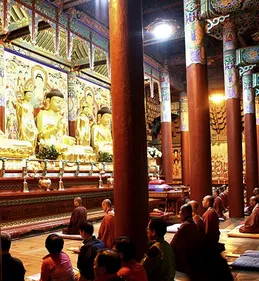 Buddhist monks chanting in a large decorated hall with columns