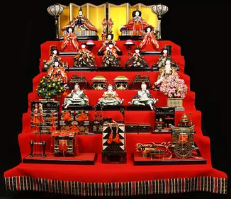 seven tier display of Japanese dolls on a platform covered with red fabric