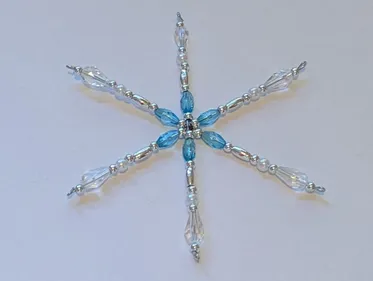 A handmade, beaded Christmas tree ornament in the shape of a snowflake