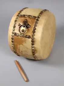 Image of a wooden and leather studded drum with a beater