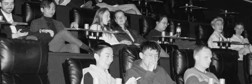 A black and white photo of students smiling and laughing in a theatre