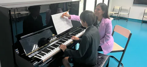 Chara (right) teaching a young student to play the piano