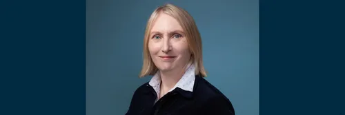 Professor Carol Adams facing the camera with a blue background behind her