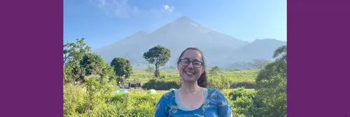 Professor Claire Horwell pictured outside with foliage and a view of a volcano behind her
