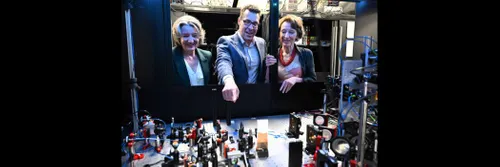 A man pointing to some scientific equipment, as he speaks with two women