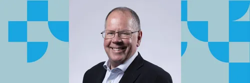 Man wearing glasses and a suit with no tie smiling