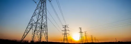 Electricity pylons with sun setting behind them