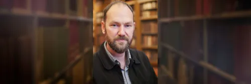 Bearded male in front of old books