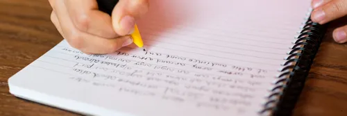 Close up of a child's hand writing on a lined piece of paper