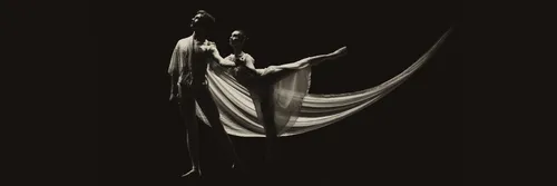 Two ballet dancers performing, in black and white with dark background