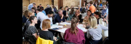 Many people sitting round tables, working informally
