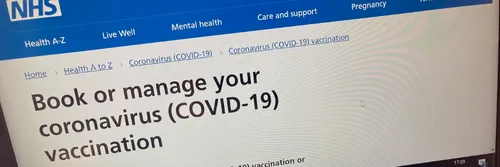 Blue background on computer screen of NHS Vaccine Booking System for Covid-19