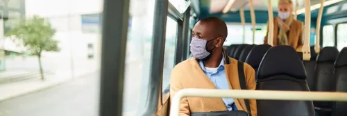 Two people on a bus, wearing face masks