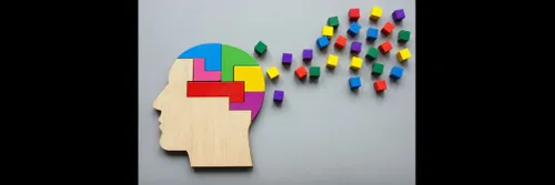 A wooden jigsaw-like picture of a head, with coloured bricks apparently flying away from it