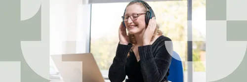 A female student with a headset on in front of a laptop