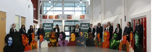 A group of school pupils with large pieces of artwork.