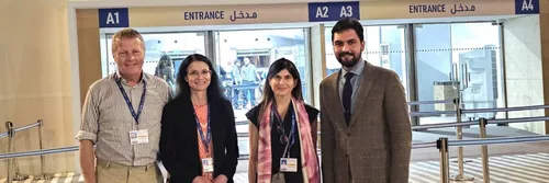 Two men and two women standing in front of a large doorway at COP28.