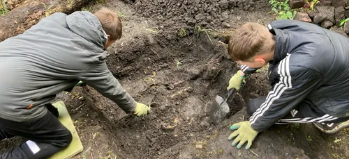 Two school pupils digging in a test pit