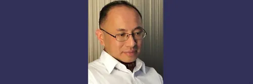 Head and shoulders picture of a man wearing glasses and looking slightly downwards and off to the side of the camera.