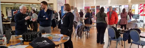 People looking at research stalls and talking to each other in a large event space